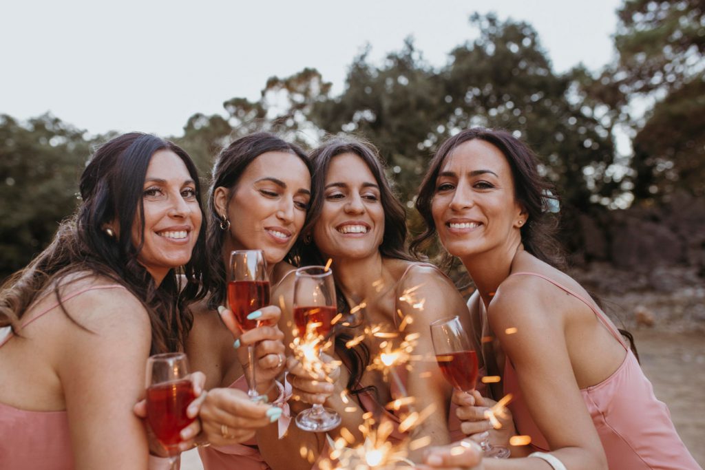 Group of girlfriends at a bachelorette gathering with drinks and sparklers